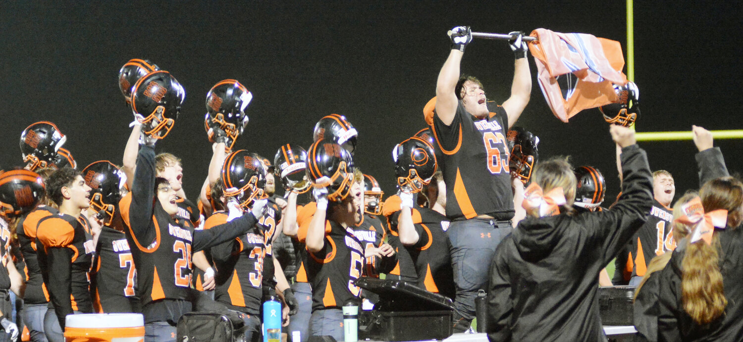 Hayden Shoemaker (far right) holds the Owensville flag while he and his teammates sing the Owensville High School song after Owensville's 48-14 district-opening victory over Lutheran South.